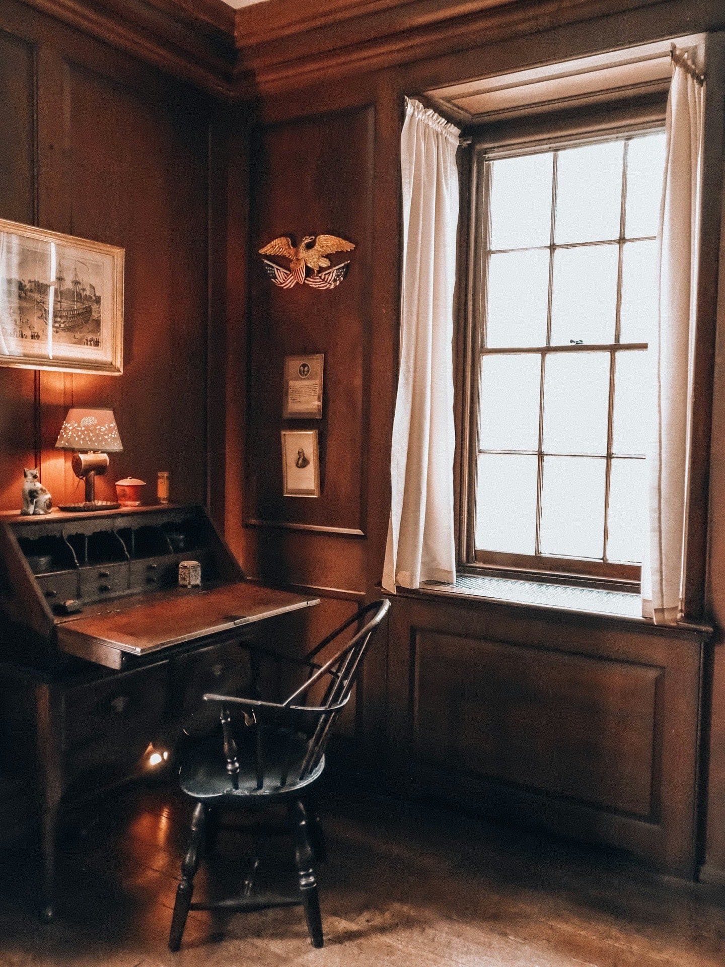 Estudio privado con paneles de madera oscura, escritorio antiguo y luz cálida de ventana