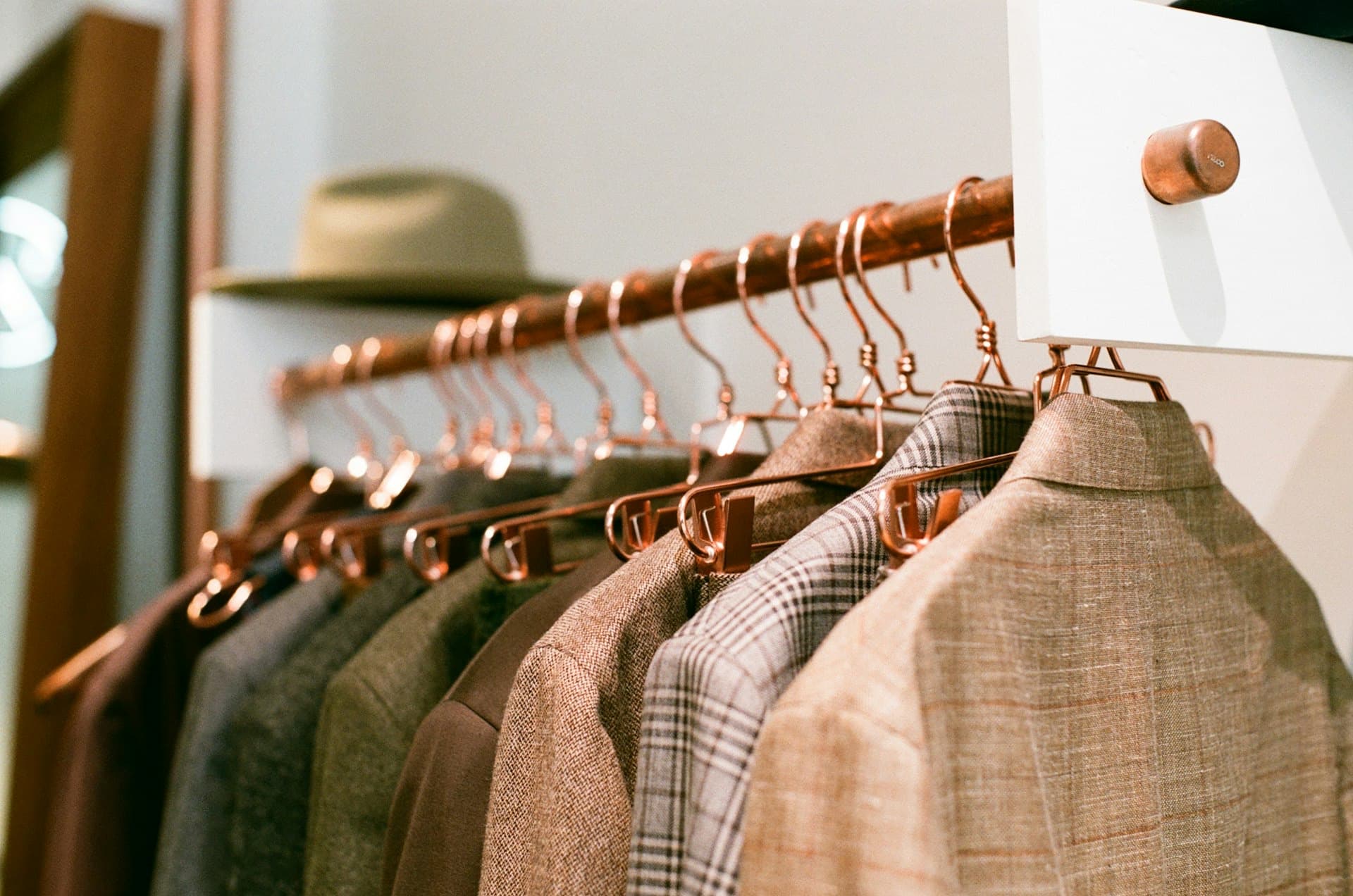 Blazers de tweed y lino colgados en percheros de cobre en un showroom